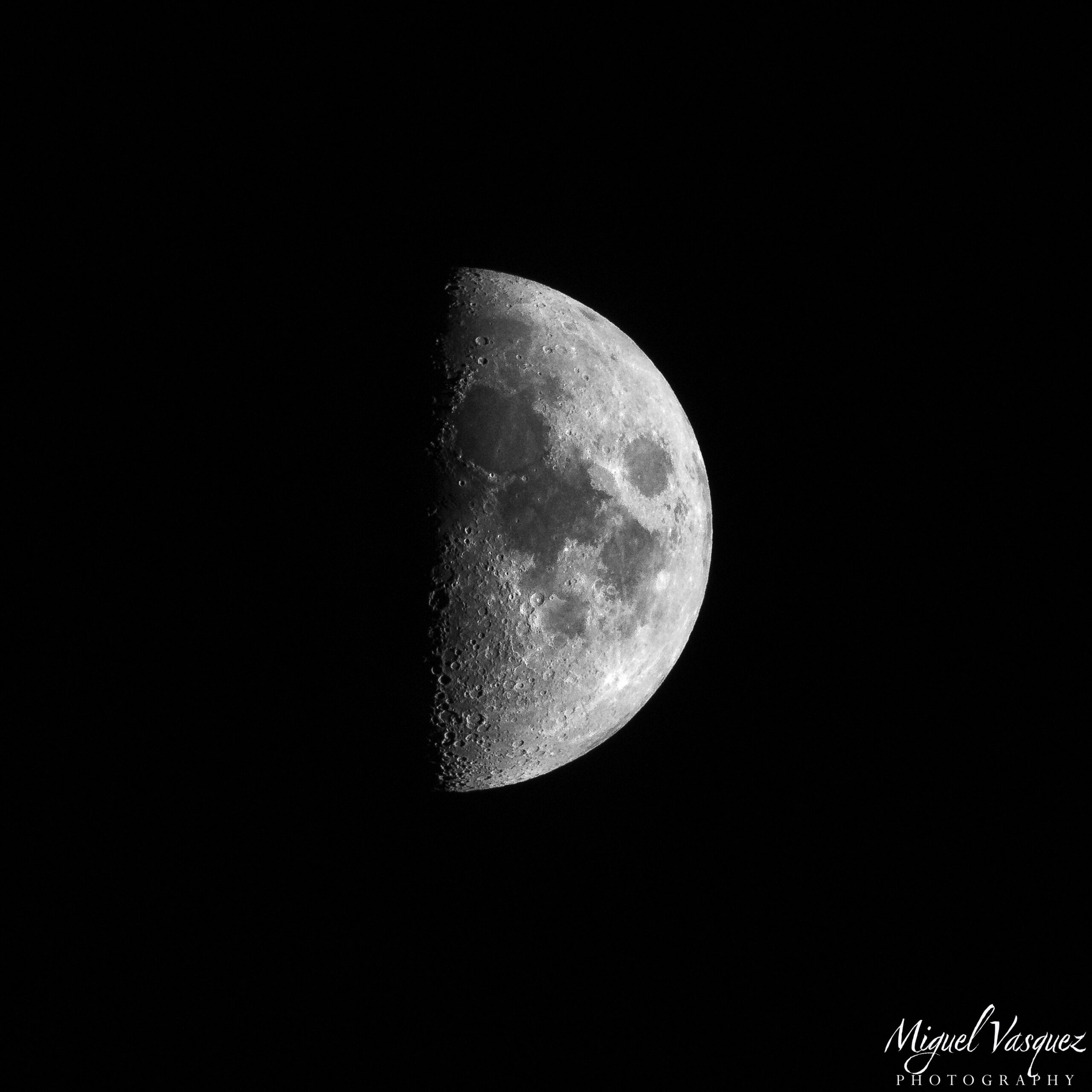 Close-up telephoto photo of a half moon glowing against a dark night sky