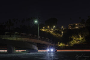 Night photo of the Santa Monica bluffs pedestrian bridge over PCH with car light trails