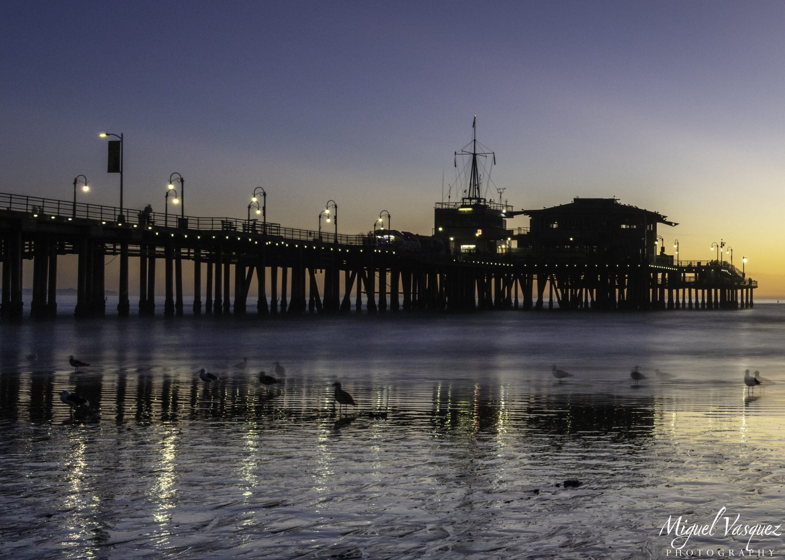 Santa Monica Pier at sunset with warm light reflecting on the water