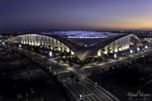 Aerial view of SoFi Stadium lit up at sunset in Inglewood, California